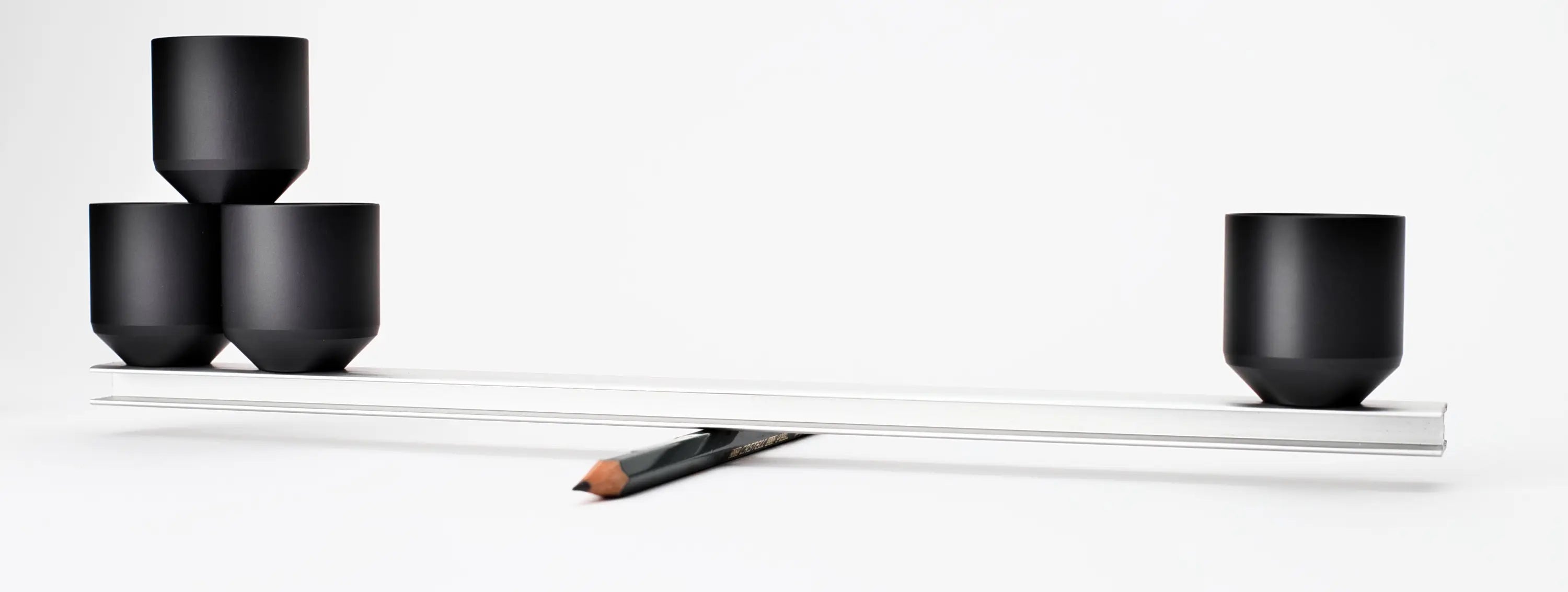 Schwarze matte Keramiktassen mit einer eleganten silbernen Balkenwaage in einer minimalistischen geometrischen Anordnung für ACUS M1 Grip Heavy