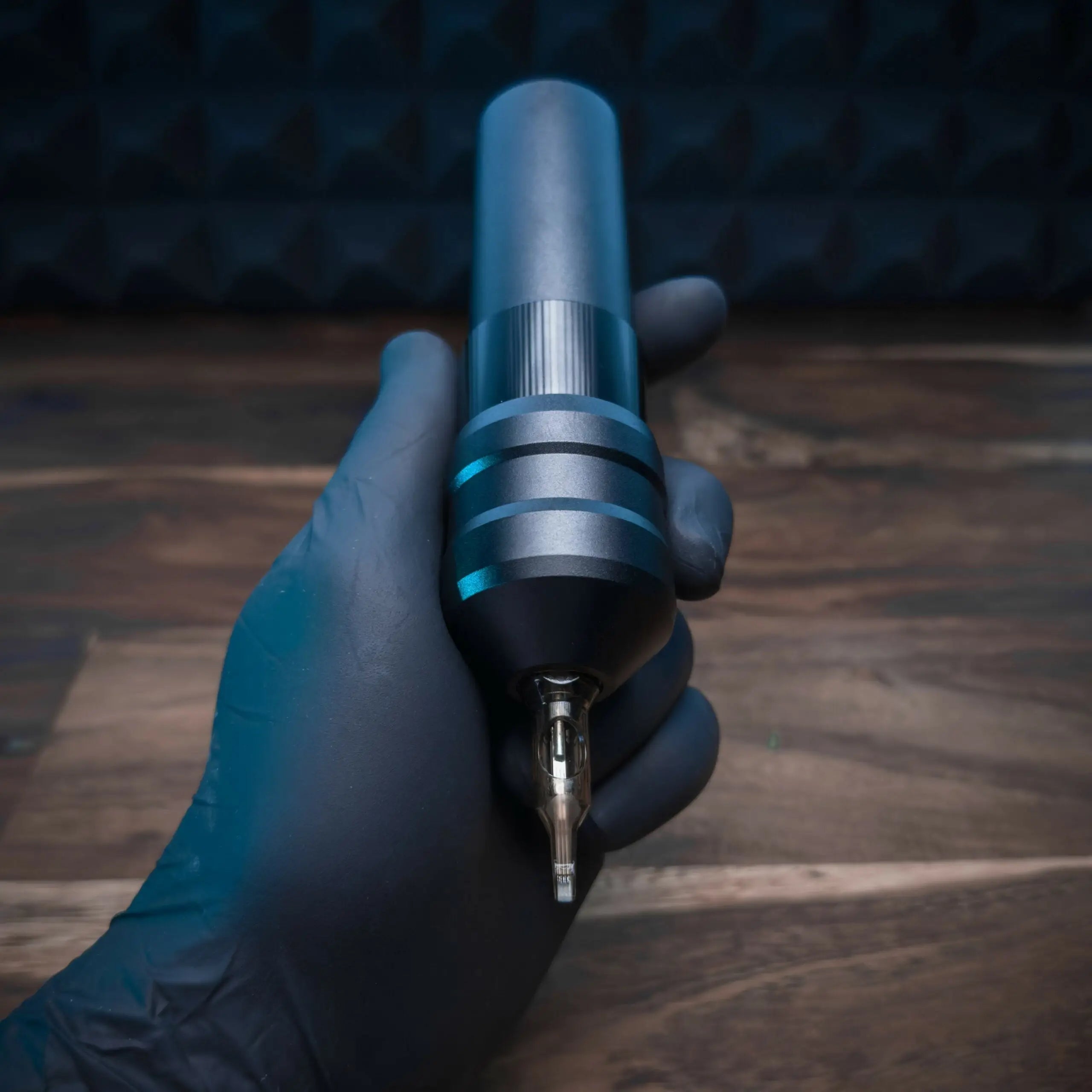 Eine elegante, mattschwarze und silberne ACUS M1 Grip Plus Tätowiermaschine mit strukturierter Grifffläche und metallischem TIP