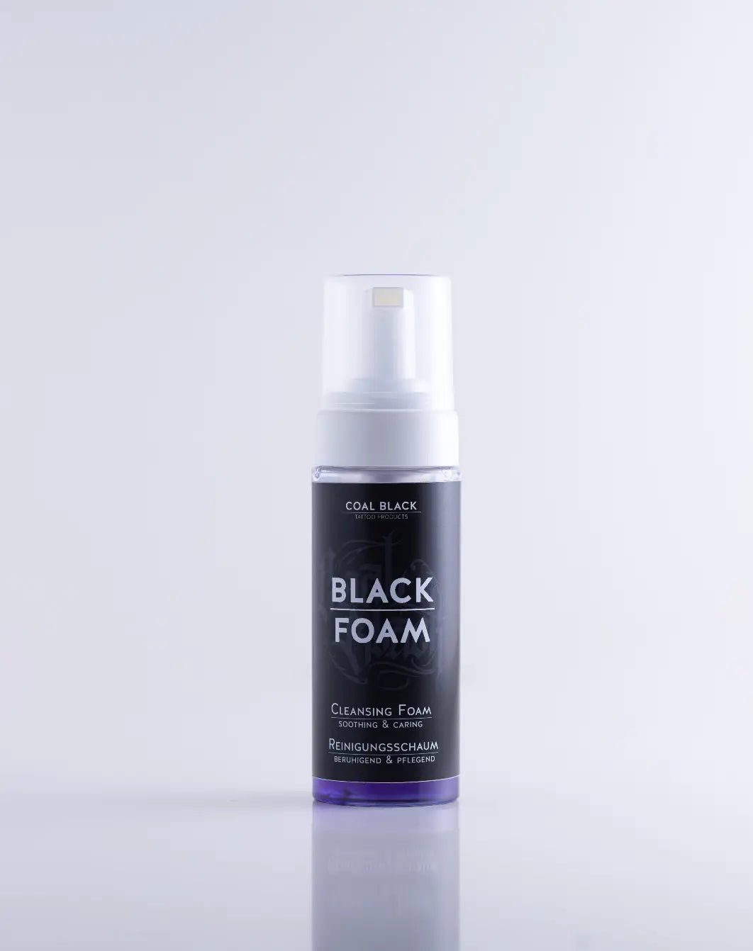 COAL BLACK schwarzer Reinigungsschaum in einer eleganten transparenten Flasche mit weißer Pumpe und violetter Flüssigkeit im Inneren