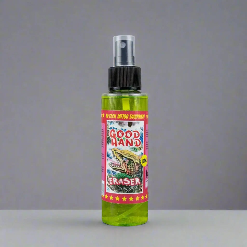 Auffällige grüne GOOD HAND Radiergummi-Sprühflasche mit schwarzer Düse und auffälligem rotem Etikett auf pinkem Hintergrund mit Alligator-Illustration