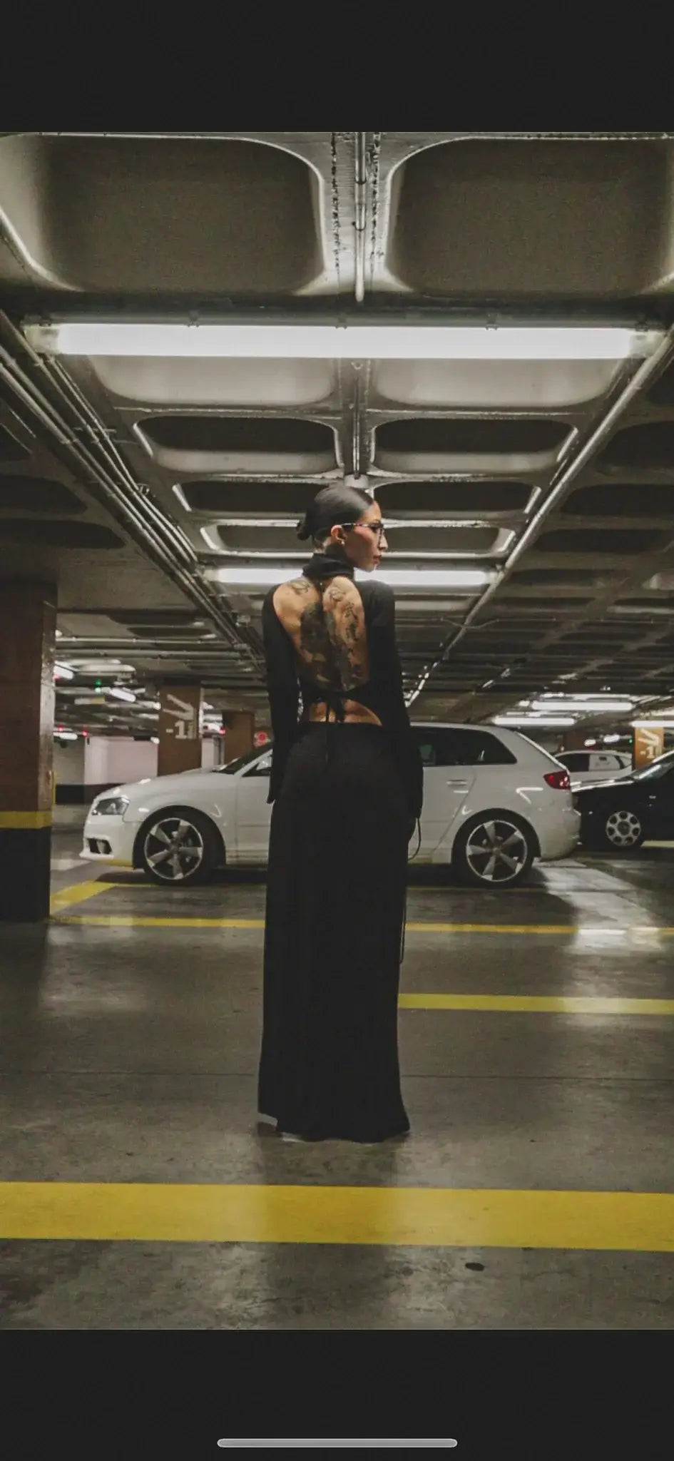 A woman wearing the back of a black kalu ibiza ibiza dj dress with long sleeves and intricate tattooed design
