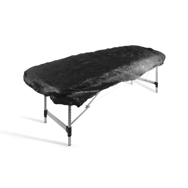 Black textured fabric elasticated bed cover draped over foldable massage table for killer ink black line set