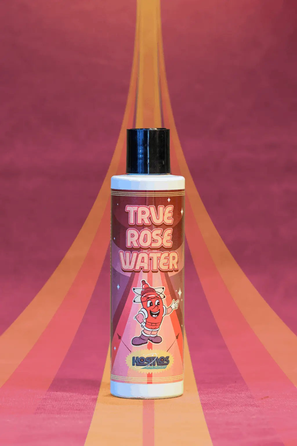 A vibrant pink and orange bottle of Kosmos true rose water with a black cap and a cartoon character design