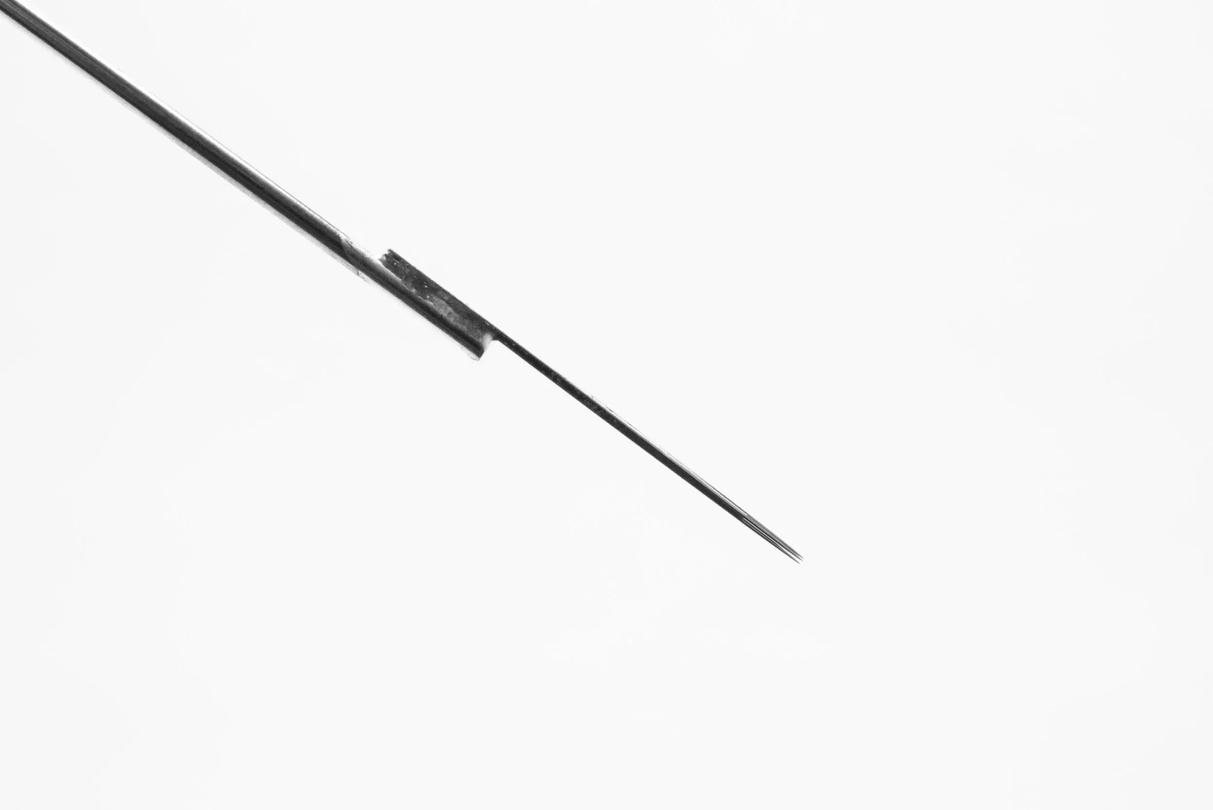A sleek metallic lotus bar needle with a sharp point and fine shaft for round liner and standard liner use