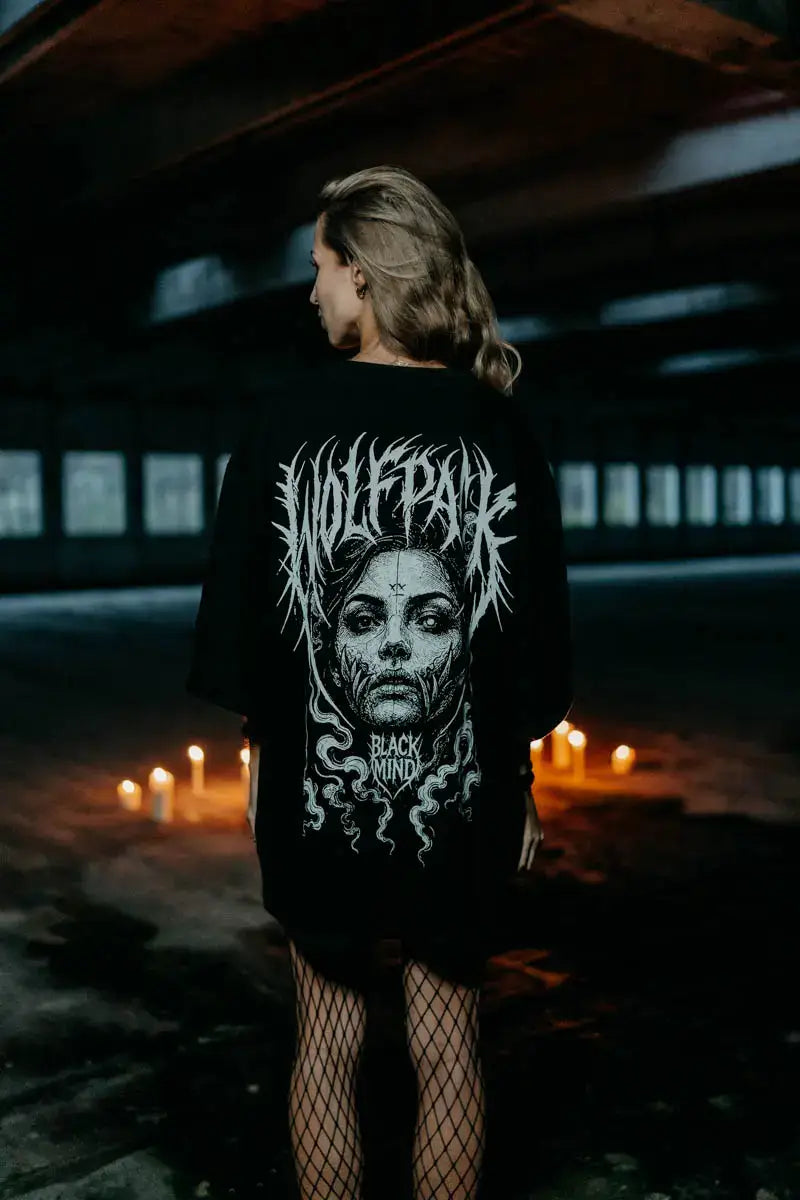 Black oversized unisex t-shirt featuring a white graphic of a woman’s face with thorny vines and wolfpack text