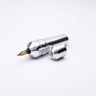 Silver metallic ACUS M1 Ayre tattoo machine with gold needle tip and matching cylindrical cap for professional use