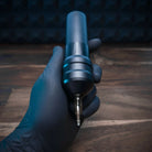 Eine elegante, mattschwarze und silberne ACUS M1 Grip Plus Tätowiermaschine mit strukturierter Grifffläche und metallischem TIP