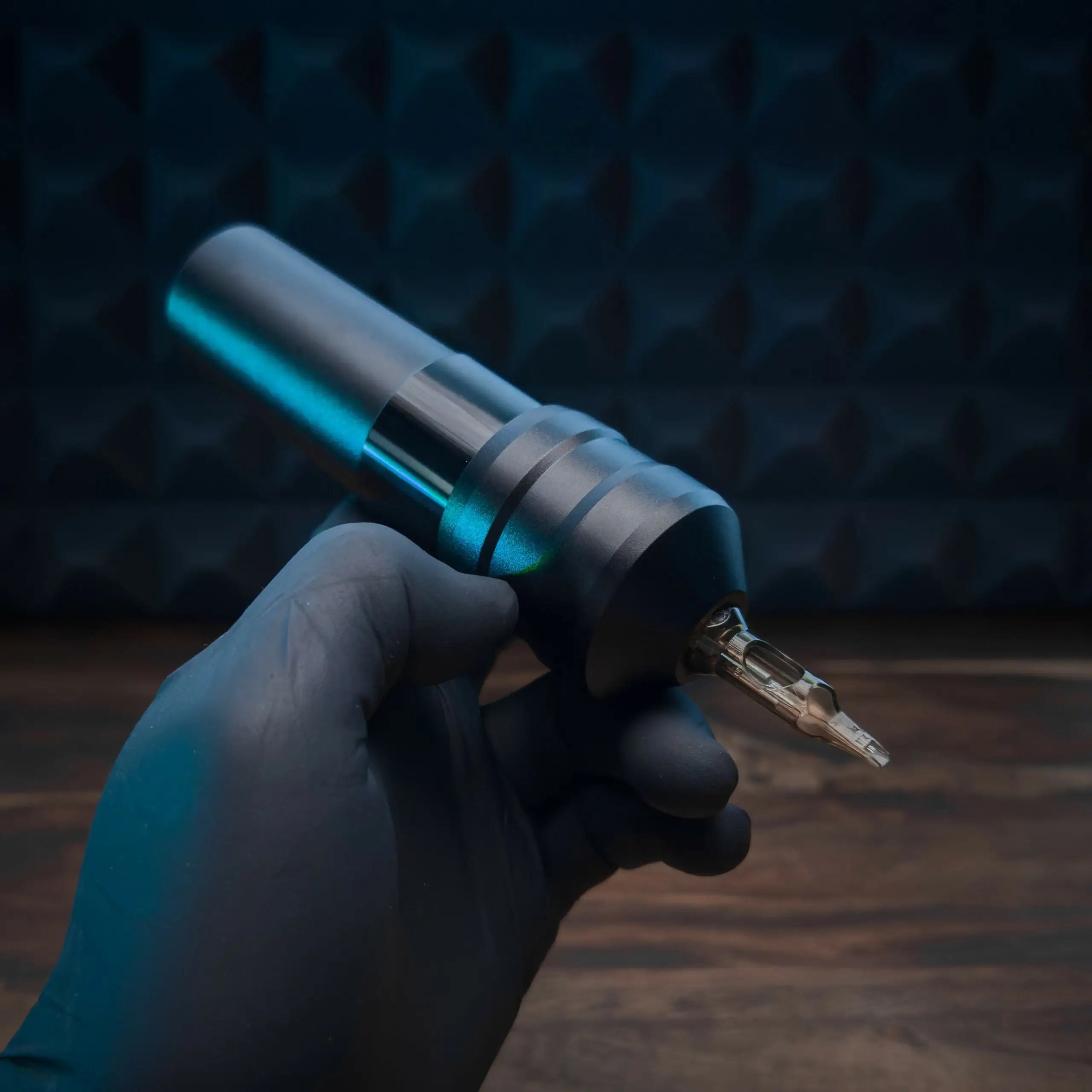 Eine elegante metallische ACUS M1 Grip Plus Tätowiermaschine mit leuchtend blauem Akzent und präzisem Nadel-TIP
