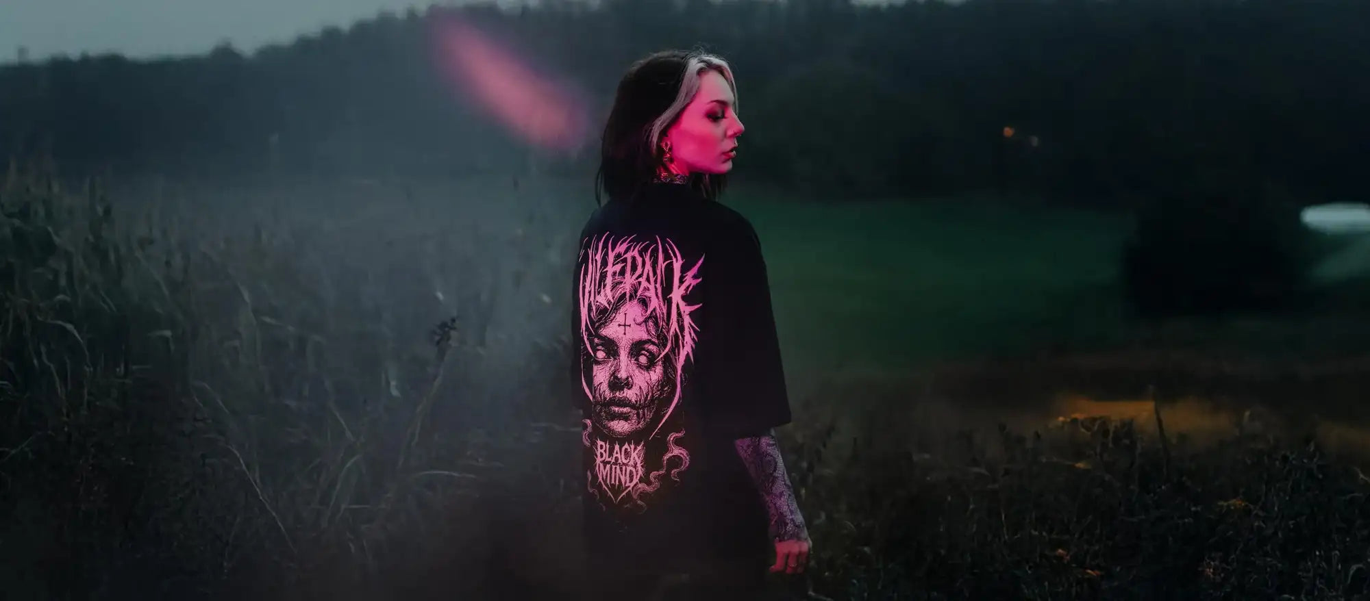 alt
Schwarzes T-Shirt mit leuchtender pinker Grafik eines Zombiegesichts und dem Text ’black mind’ darunter