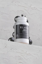 White plastic bottle of coal black black jell tattoo ink with a black label and silver metallic spheres around it