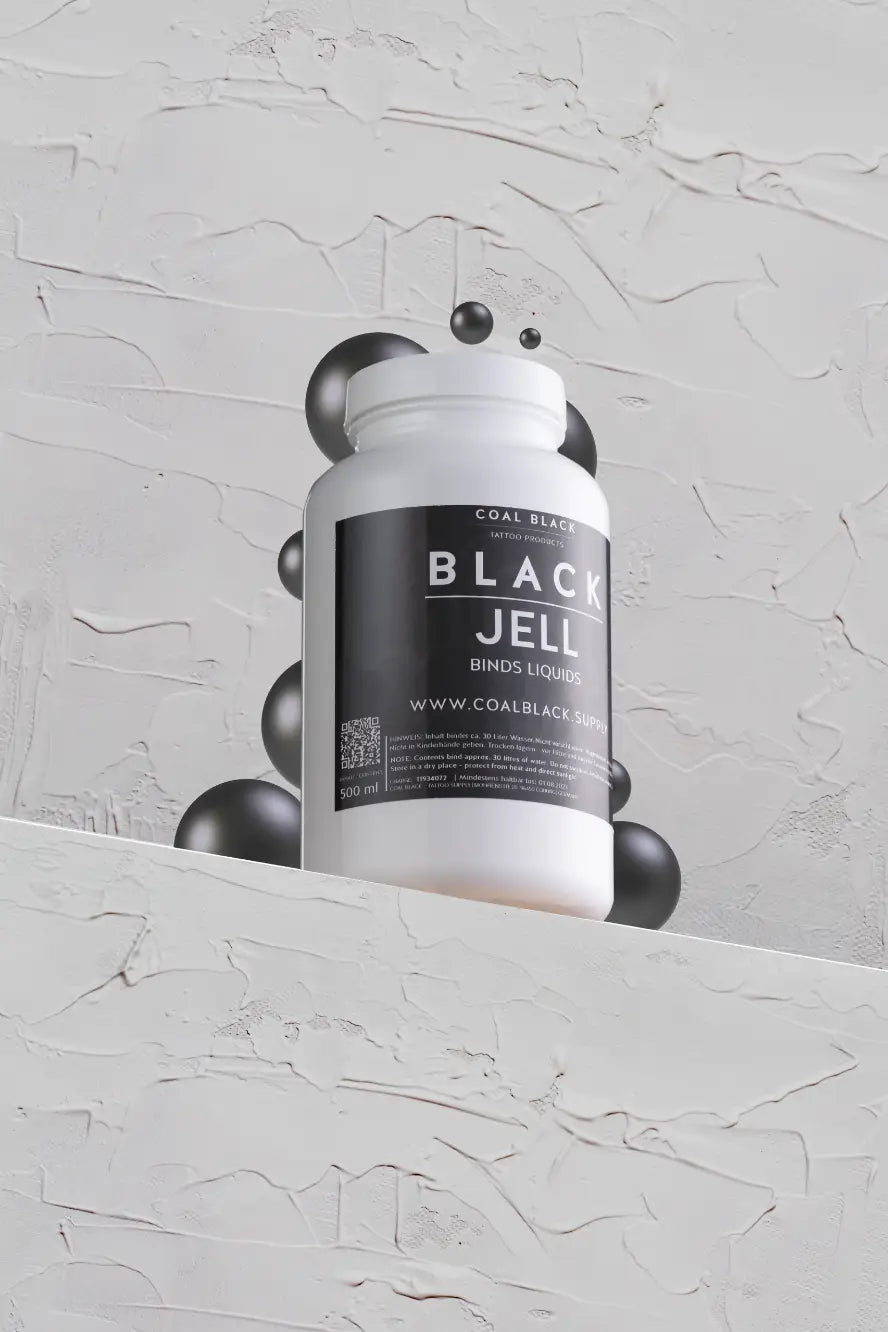 White plastic bottle of coal black black jell tattoo ink with a black label and silver metallic spheres around it