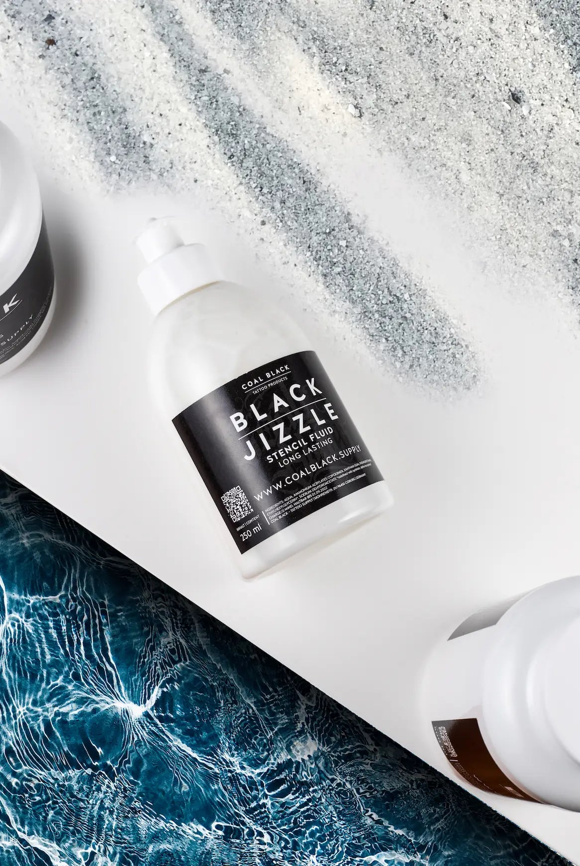 Clear plastic bottle of Coal Black black jizzle stencil fluid with white spray nozzle containing 250 ml long-lasting fluid