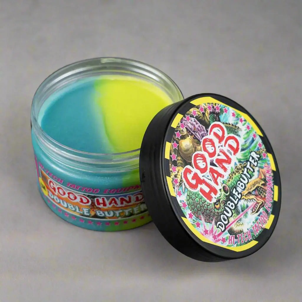 good hand Doppelbutter 250 ml in einem klaren Glasgefäß mit leuchtend blauem und gelbem Inhalt und einem farbenfrohen schwarzen Deckel