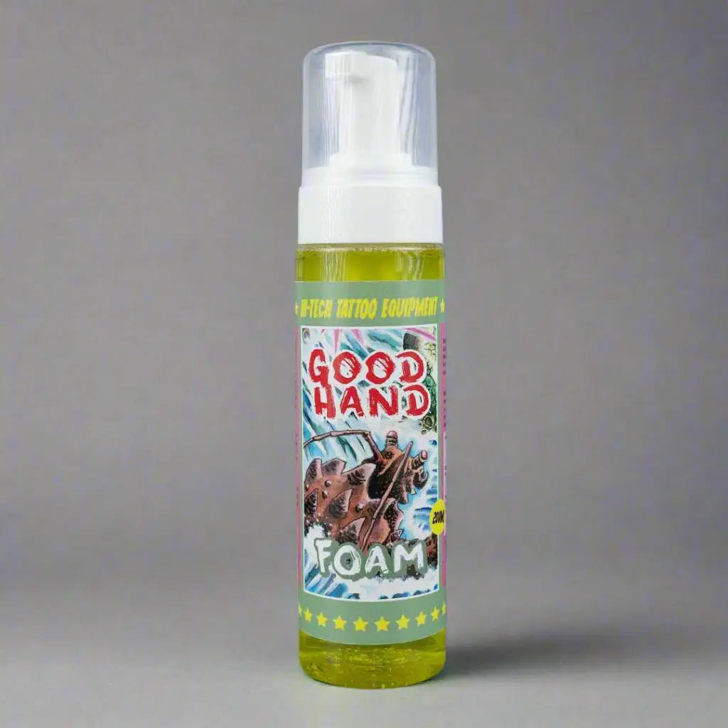 Eine leuchtend gelbe Schaum-Handdesinfektionsflasche mit weißer Pumpe und farbenfrohem Comic-Style-good hand-Schaumetikett auf grauem Hintergrund