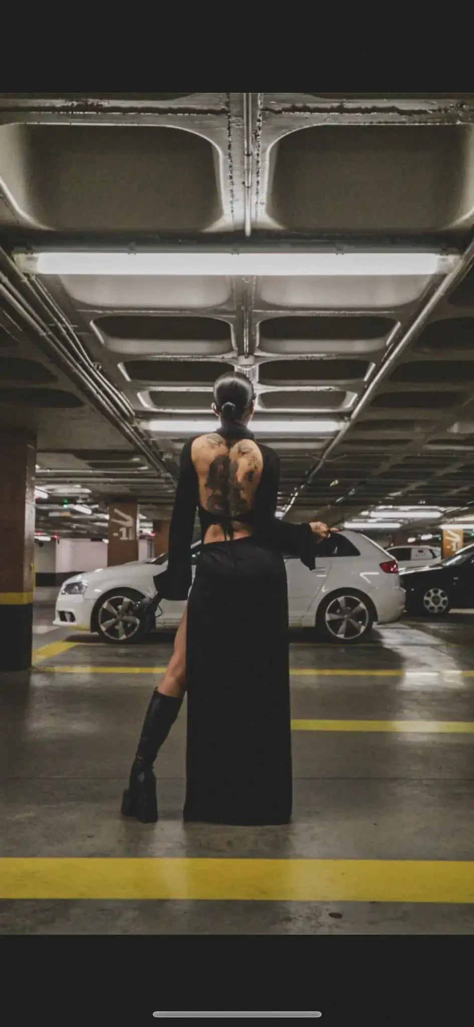 Back view of kalu ibiza black long-sleeved ibiza dj dress with high slit and intricate tattooed design showcasing vice attitude