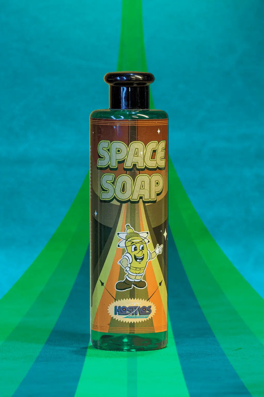 A vibrant green bottle of Kosmos space soap with a retro-style label and cartoon astronaut character design