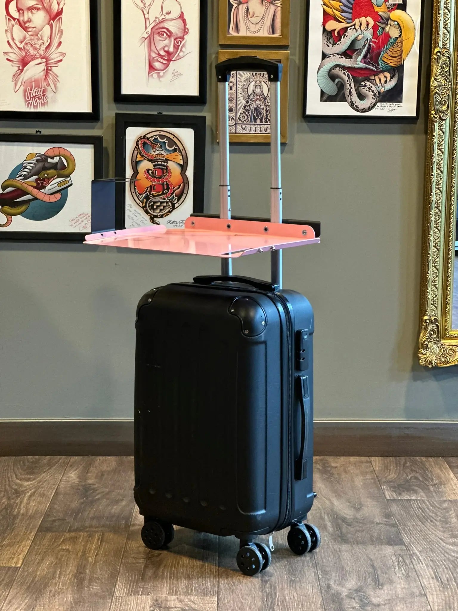 Schwarzer Hartschalenkoffer mit ausgezogenem Teleskopgriff und rosa Kunststoffablage oben, Reisetisch Lt Tattoo