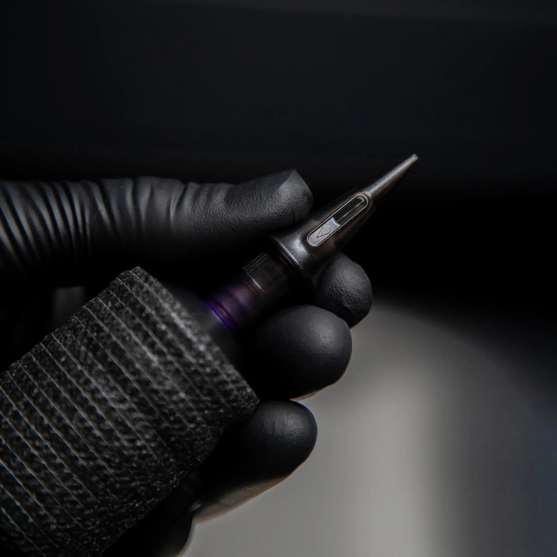 Black piranha cartridge fine line tattoo machine with textured grip and metallic needle tip for precision work