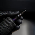 Schwarze PIRANHA cartridge Fine-Line-Tätowiermaschine mit strukturiertem Griff und metallischer Nadel-TIP für präzise Arbeiten
