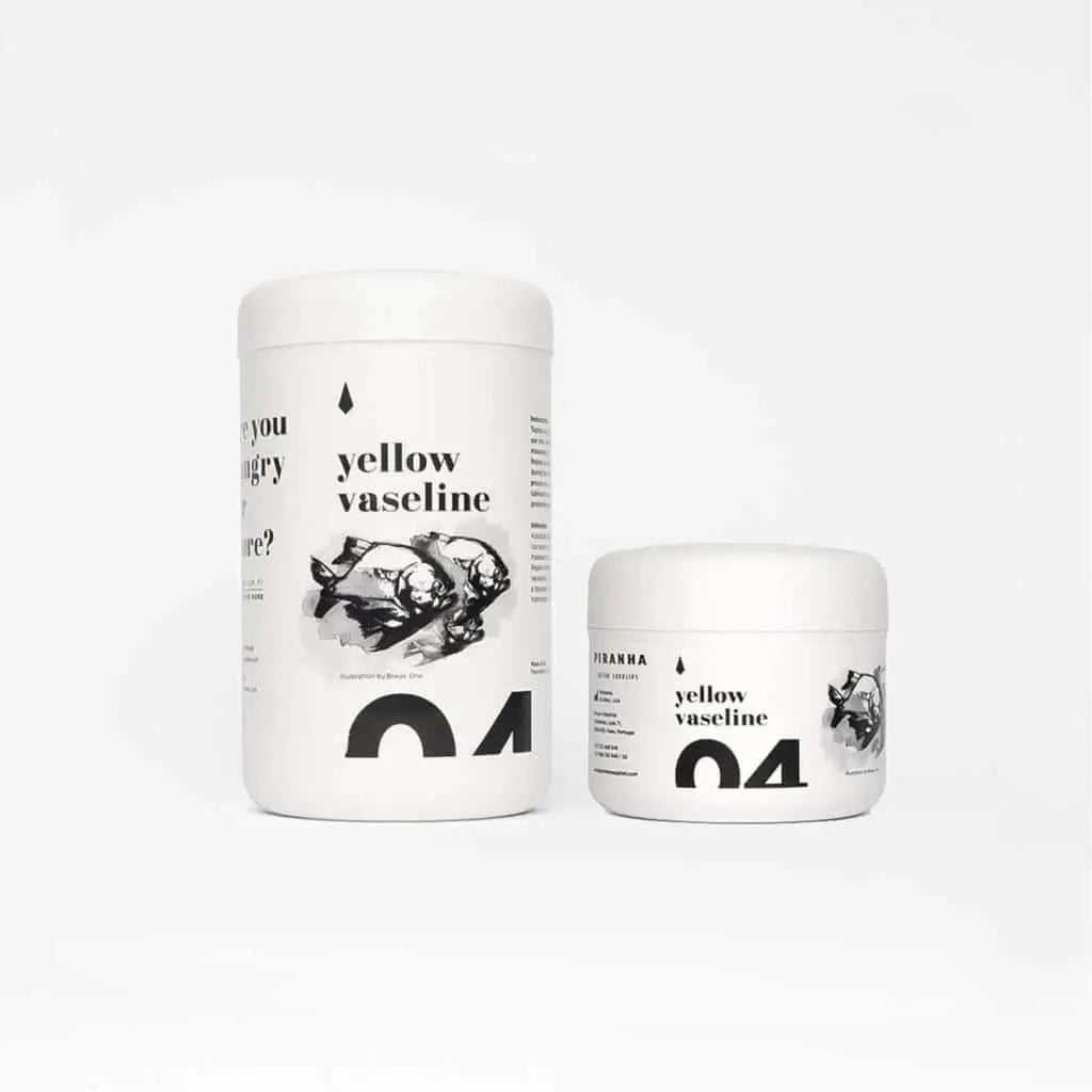 Two white cylindrical containers of yellow vaseline with black minimalist fish labels from piranha 250ml product line