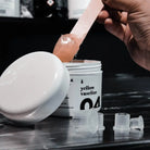 White cylindrical jar of piranha yellow vaseline 250ml with translucent peach petroleum jelly scooped by pink wooden spatula