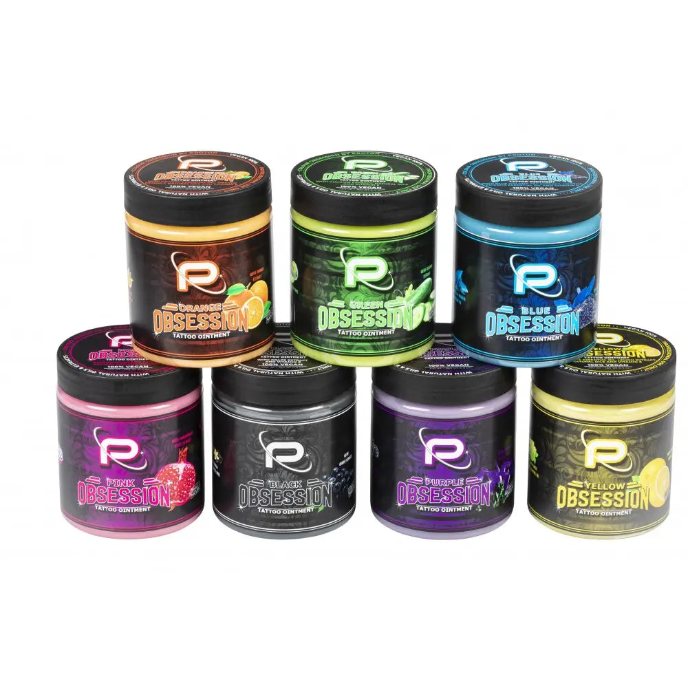 Six cylindrical jars of proton colours obsession tattoo butter balm in vibrant colors with black lids and brand labels
