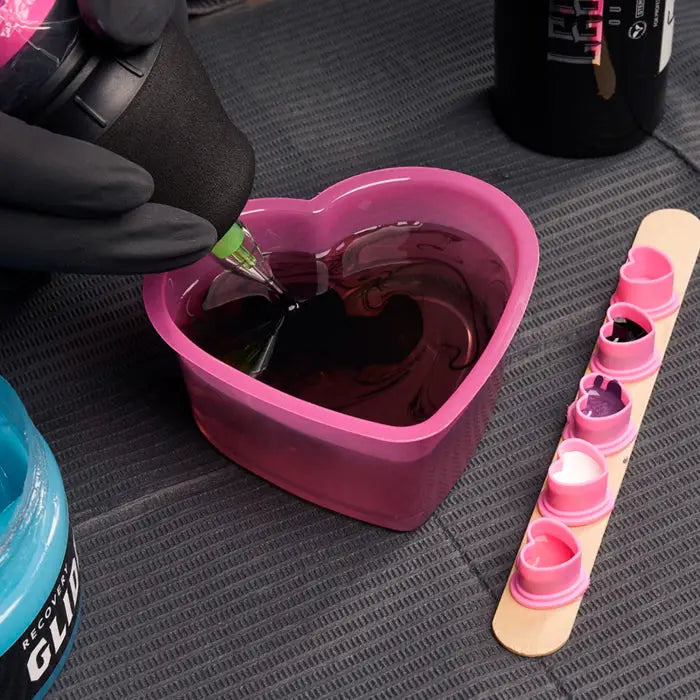 Pink heart shaped silicone SAFERLY rinse cup filled with dark red liquid 150ml capacity for safe rinsing use