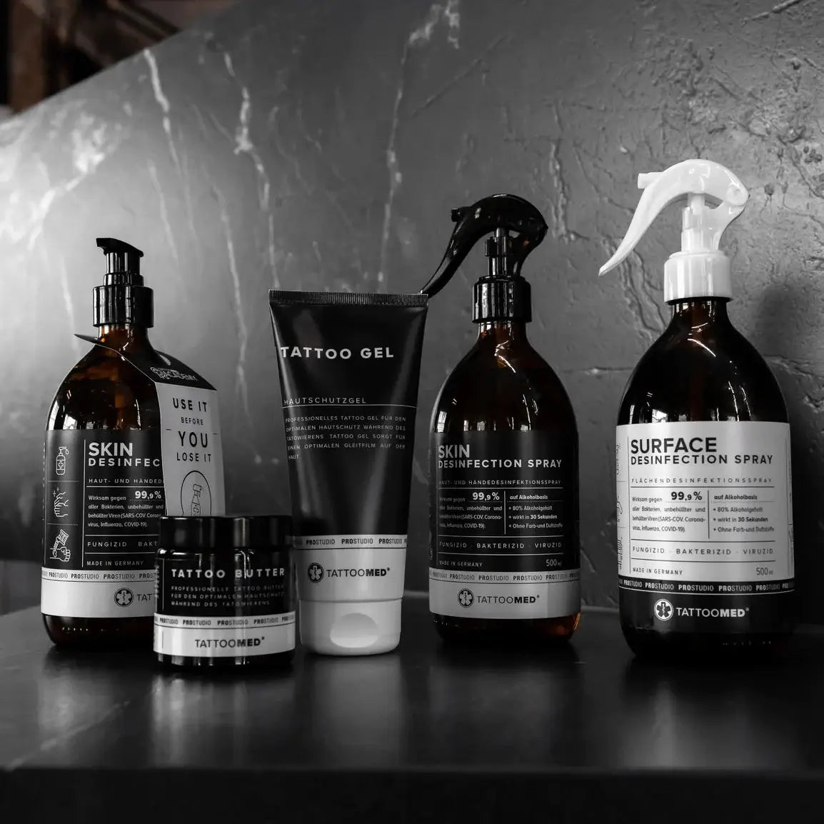 Set aus professionellen TATTOOMED Tattoo-Nachpflegeprodukten in eleganten dunklen Glas- und mattschwarzen Behältern mit weißen Etiketten