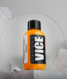 A vibrant orange liquid-filled vice alvarillo bottle with a black cap and bold white vice colors branding label