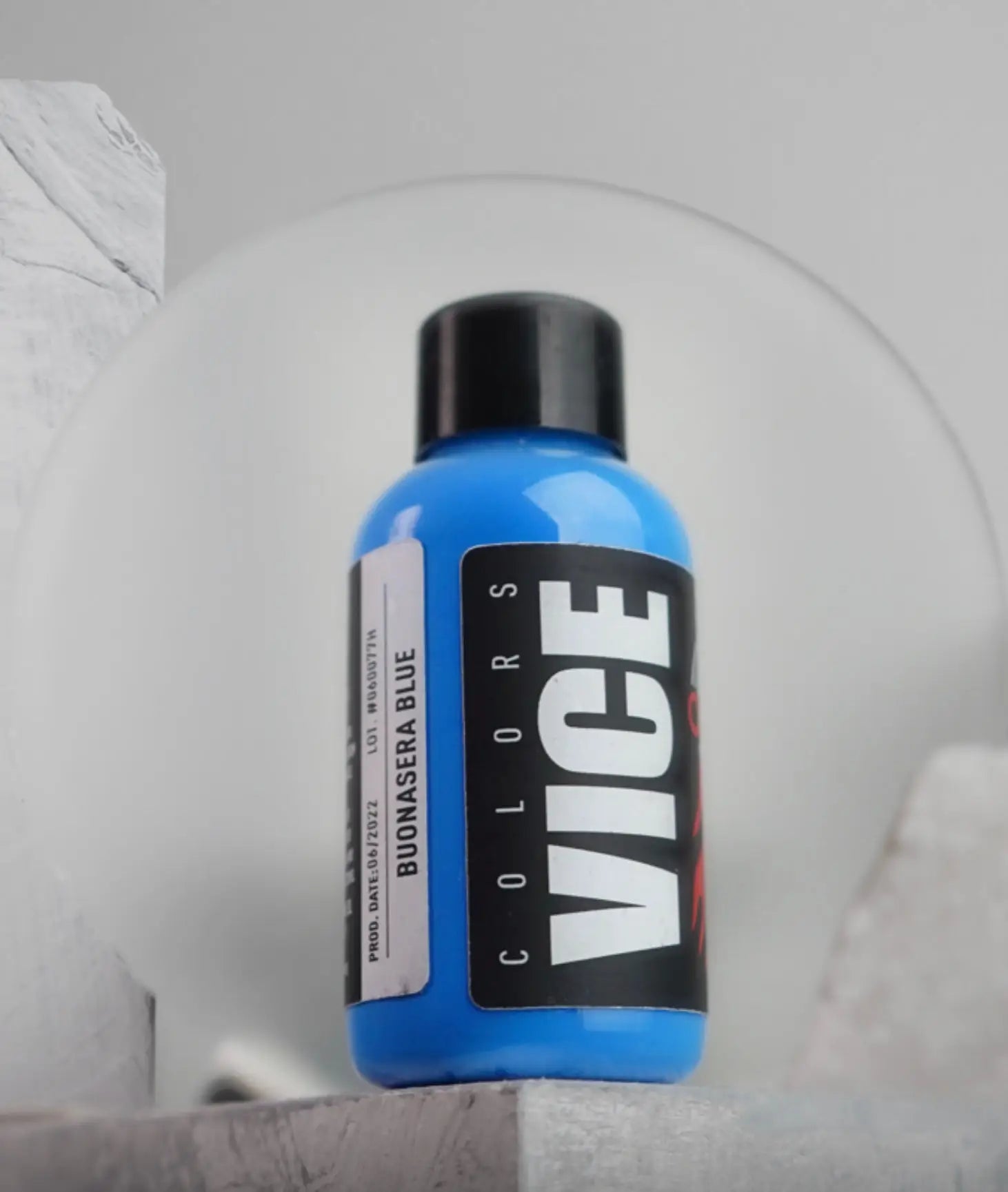 A vibrant blue bottle of vice colors paint with a sleek black cap and bold white lettering labeled buonasera blue