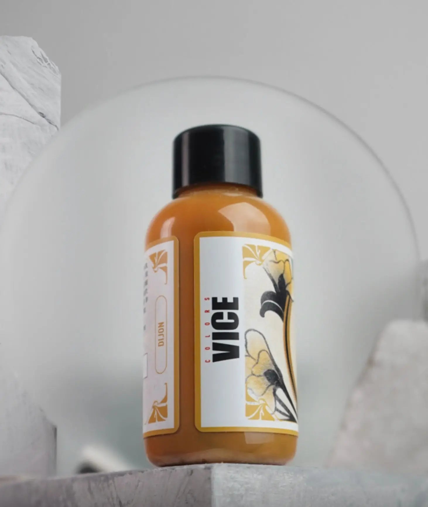 A sleek amber vice colors bottle with a black cap and floral label from the vice dijon daniels bauti set