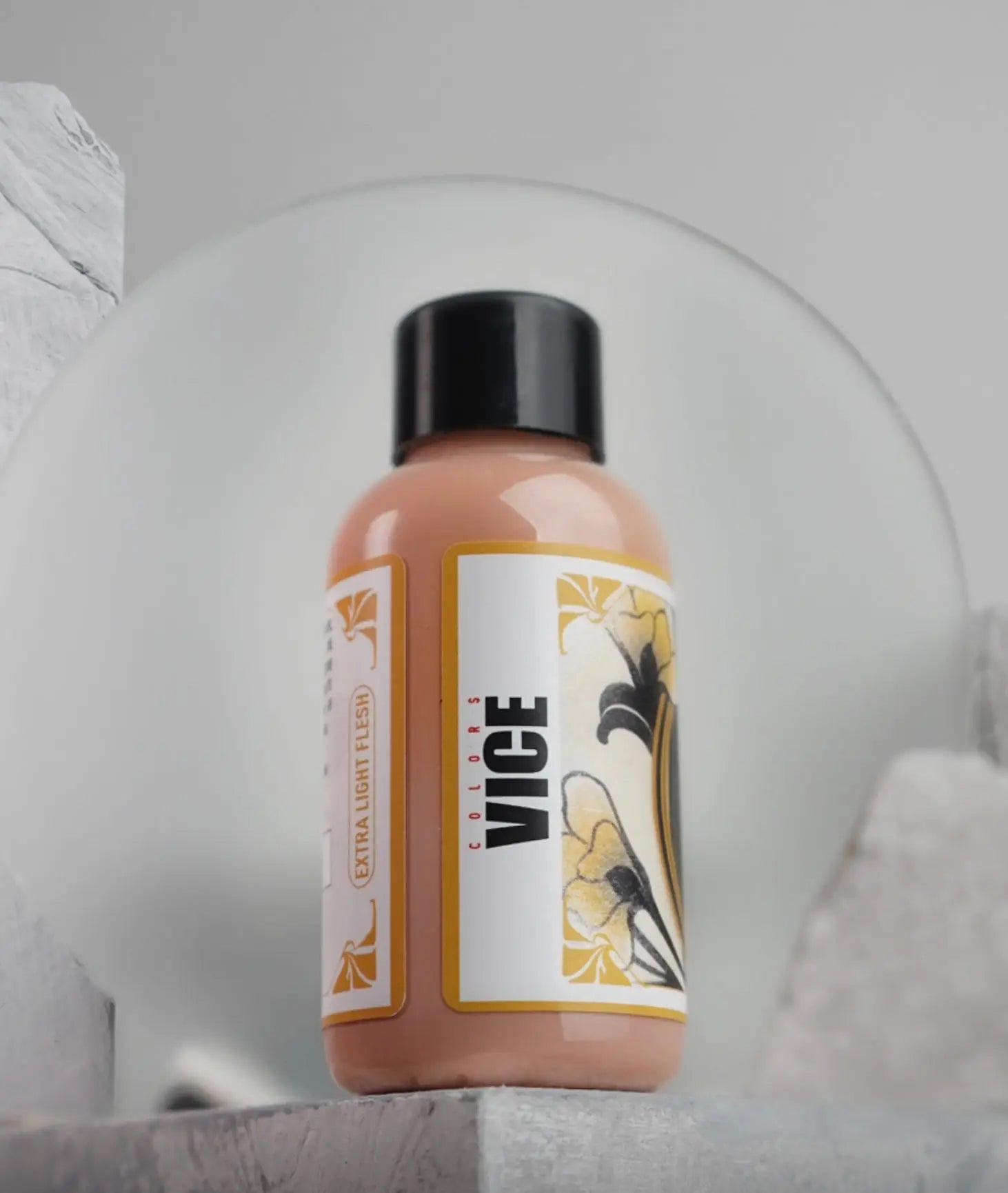 A sleek peach-colored vice extra light flesh liquid makeup bottle with a black cap and floral label from daniels bauti set