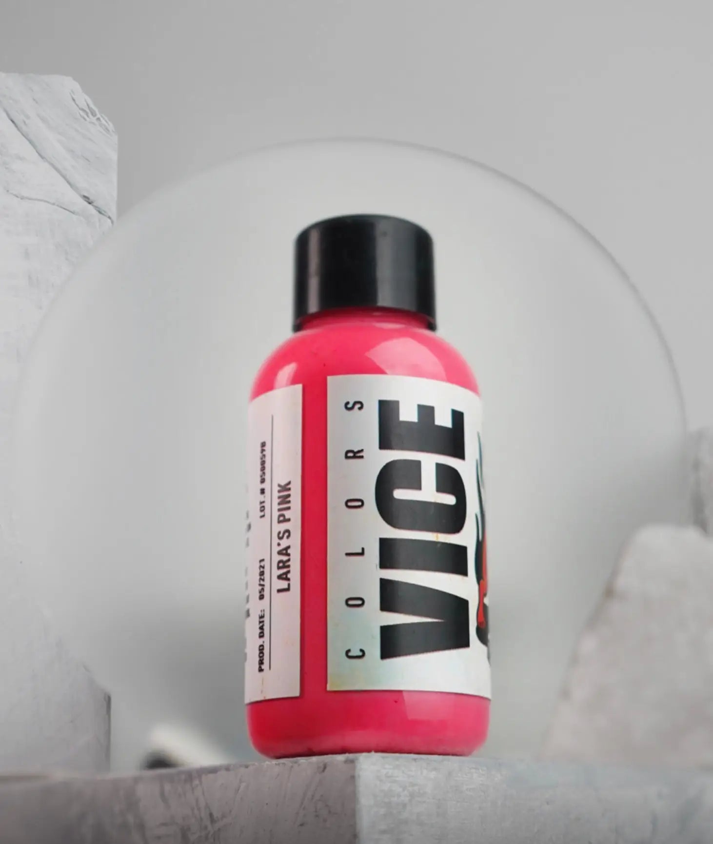A vibrant pink vice colors paint bottle with a black cap and white label for creative art projects