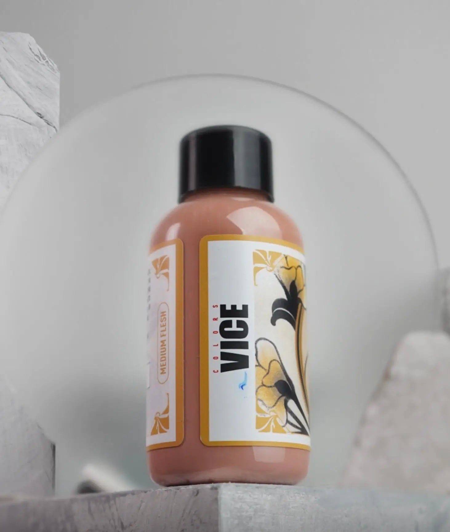 A sleek peach-colored bottle of vice colors medium flesh acrylic paint with a black cap and floral label in daniels bauti set