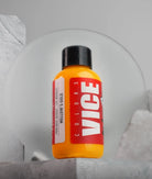 A vibrant orange bottle of vice colors mellows gold paint with a black cap and bold red label for creative use