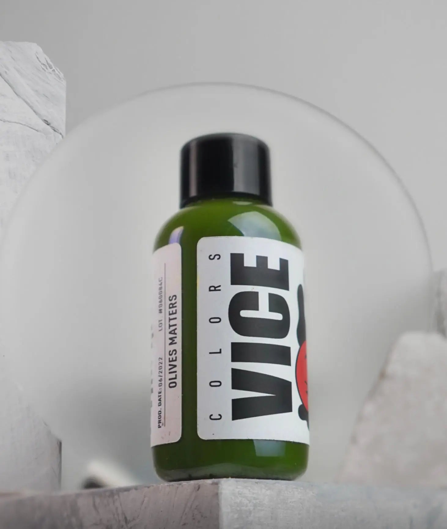 A sleek green glass bottle with black cap and white vice label reading olives matter for premium olive oil