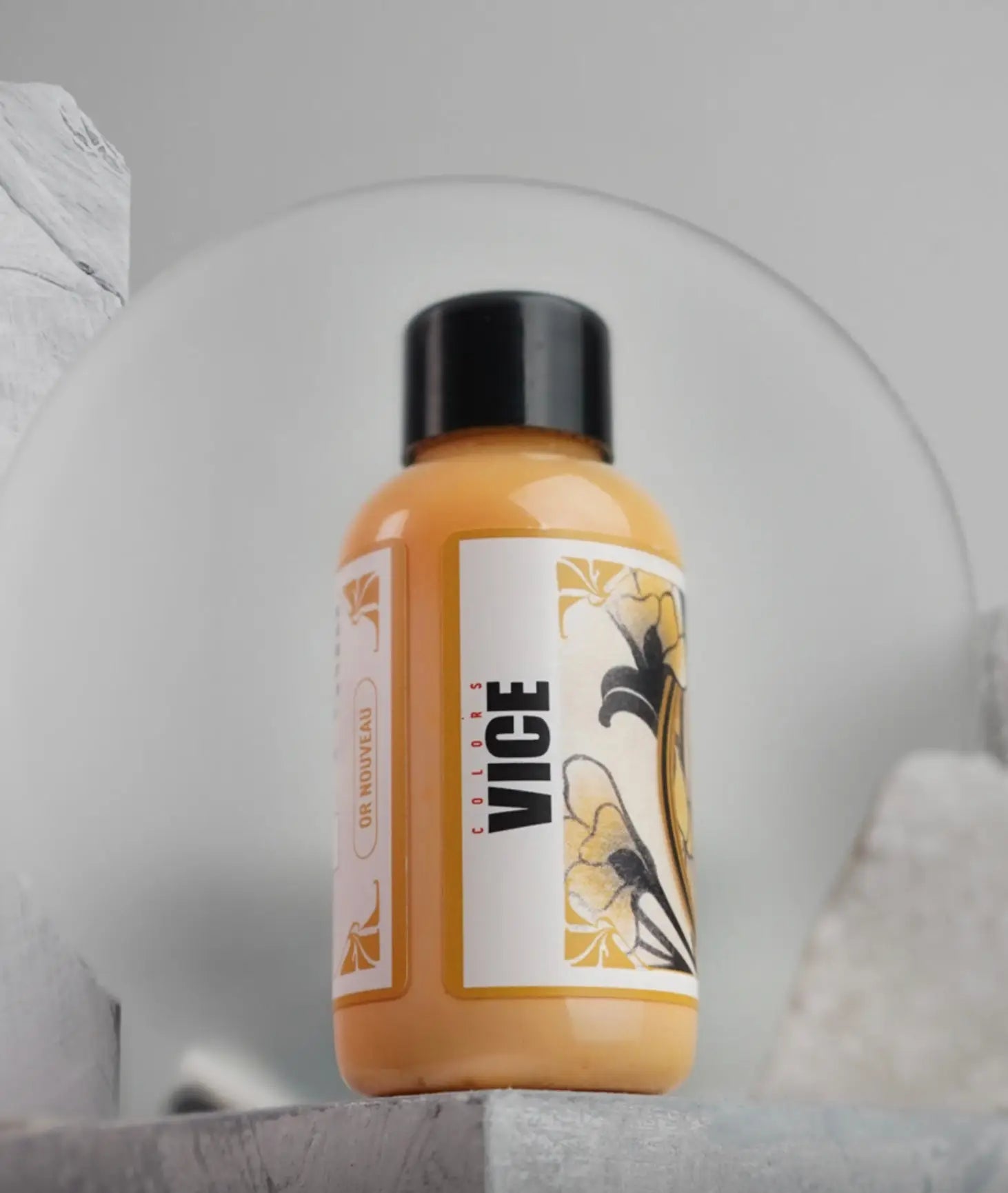 A sleek orange vice bottle with black cap and floral label in the or nouveau daniels bauti set product line
