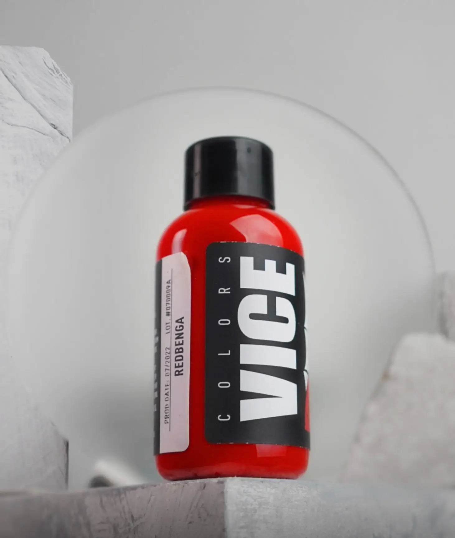 A vibrant red glossy plastic bottle of vice colors hair dye redbenga with a black cap and bold white lettering on the label