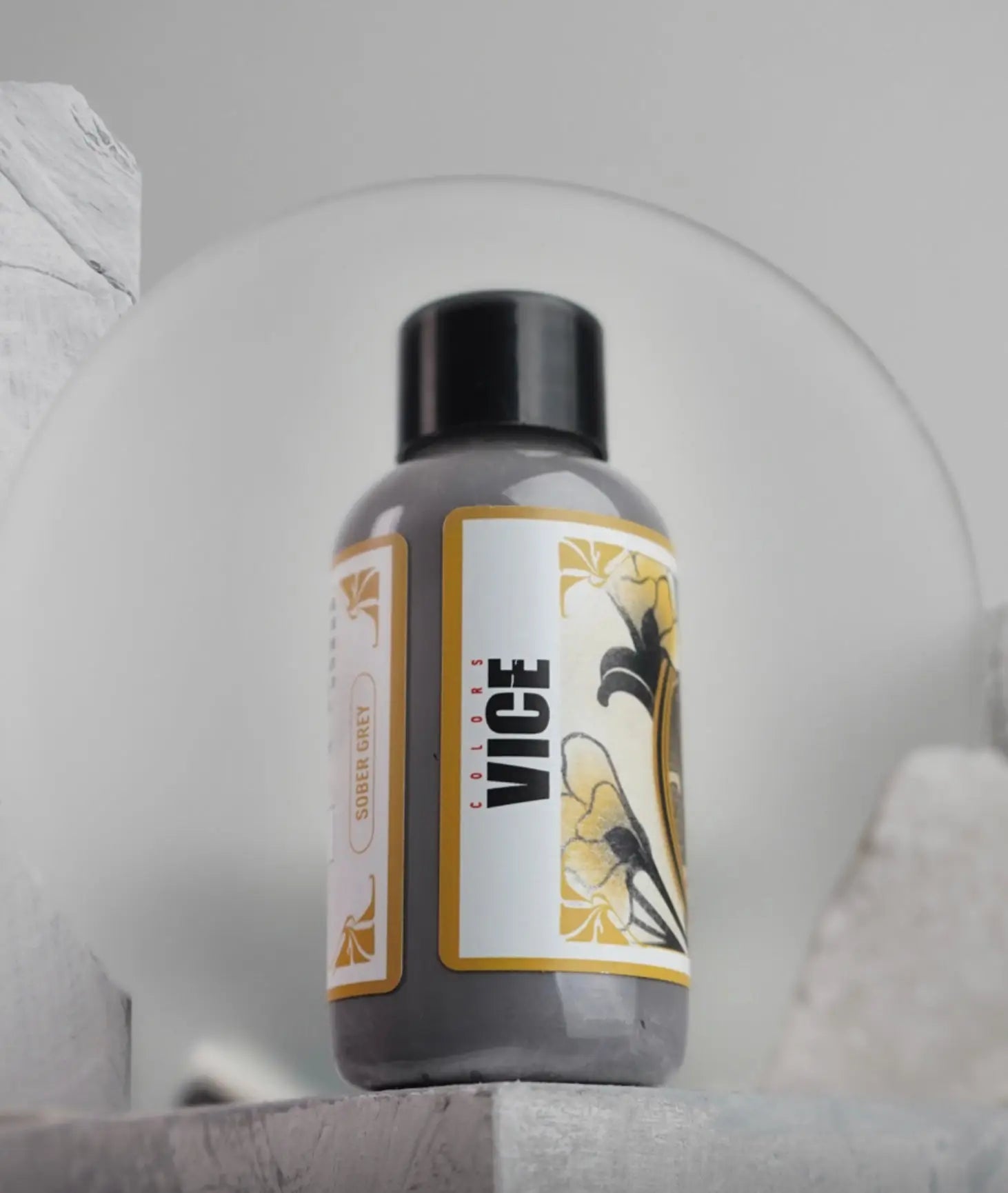 A sleek dark gray vice colors border gray nail polish bottle with black cap and ornate gold floral label from daniels bauti set