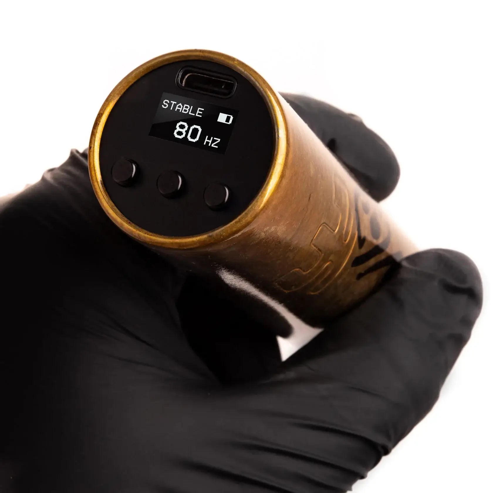 Gold-colored cylindrical tattoo machine with black digital display showing stable 80 hz and three control buttons by Vlad Blad