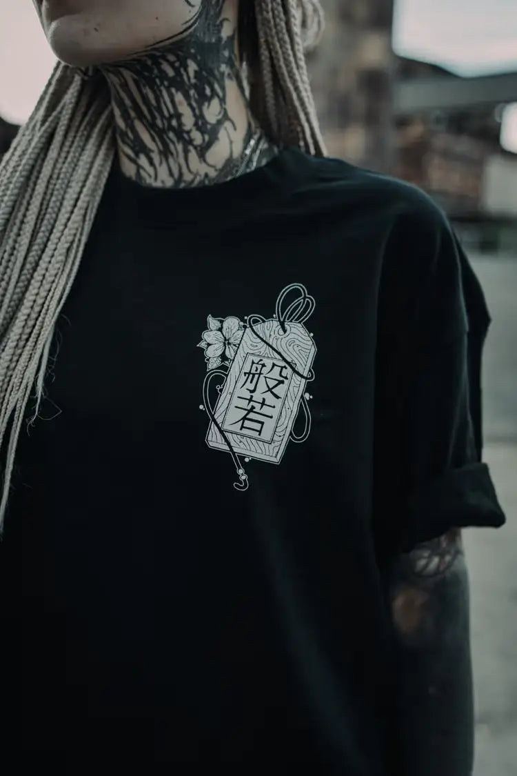 alt
T-shirt nera oversize unisex con grafica talismano giapponese in line art bianca con kanji e dettagli floreali, indossa la taglia