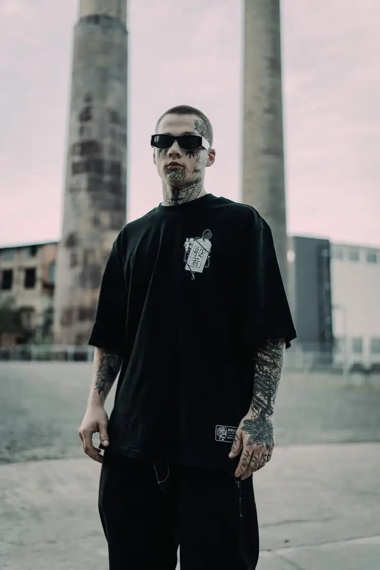 Black oversized tee unisex wolfpack hannya with white chest graphic and small rectangular brand tag at bottom hem wears size