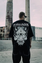 Black oversized tee unisex with large white oni mask graphic and japanese text on the back wears size shown