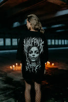 Black oversized unisex t-shirt featuring a white graphic of a woman’s face with thorny vines and wolfpack text